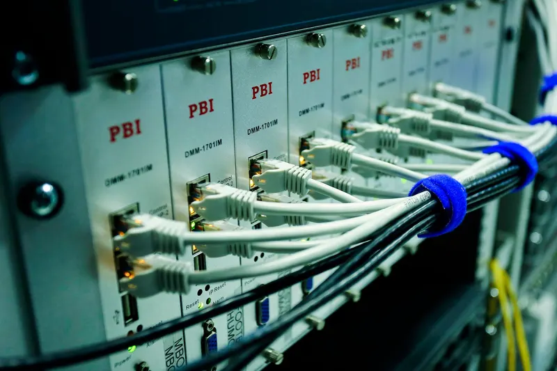 Network cables plugged into equipment panels in a rack.