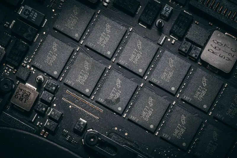 A dark circuit board carrying several integrated circuits in rectangular packages.