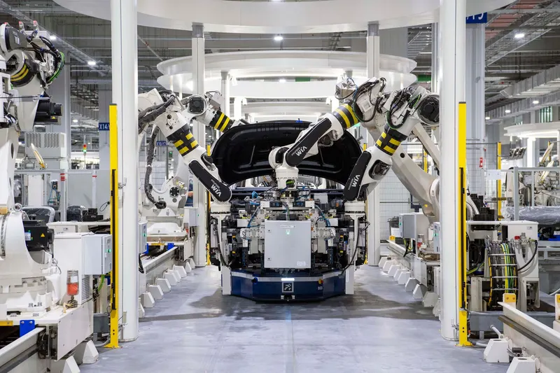 Industrial robot arms working around a car body on a production line.